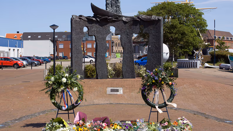 Het monument Schaduwen van het Licht met op de achtergrond de parkeerplaats van de marinewerf Willemsoord.