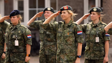 Koningin Máxima brengt met haar baret op de militaire groet tussen drie andere militairen. 