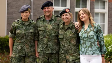 Koningin Máxima en koning Willem-Alexander poseren samen met hun dochters Amalia en Alexia. Allen dragen een groen vlekkenpak met baret, behalve Alexia.