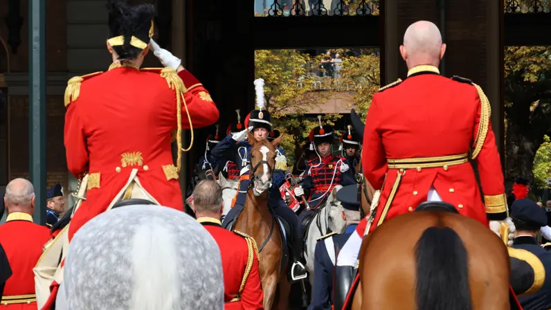 Een ruiter in uniform op zijn paard staat voor een aantal mensen in uniform.