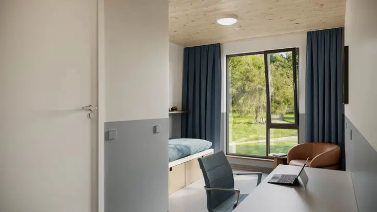 Een eenpersoons slaapkamer met stoel en bureau.