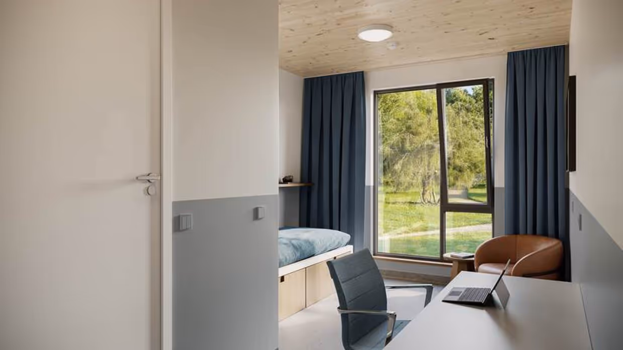 Een eenpersoons slaapkamer met stoel en bureau.