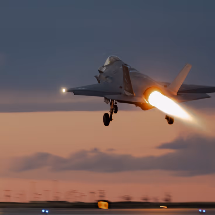 In het donker opstijgende F-35 met zichtbare naverbrander. De lucht is paars-oranje.