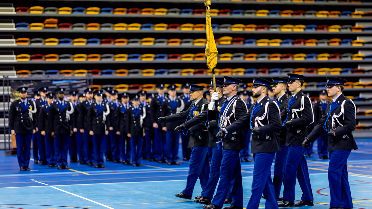 Marechaussees in ceremonieel tenue treden aan tijdens de beëdiging in een sporthal in Apeldoorn.