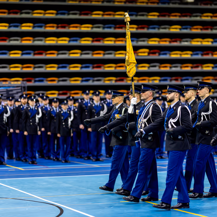 Marechaussees in ceremonieel tenue treden aan tijdens de beëdiging in een sporthal in Apeldoorn.