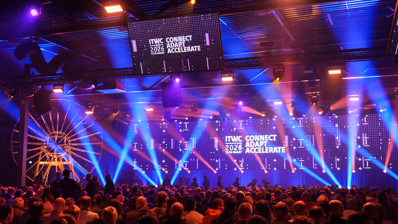 Volle conferentiezaal met lichtshow.