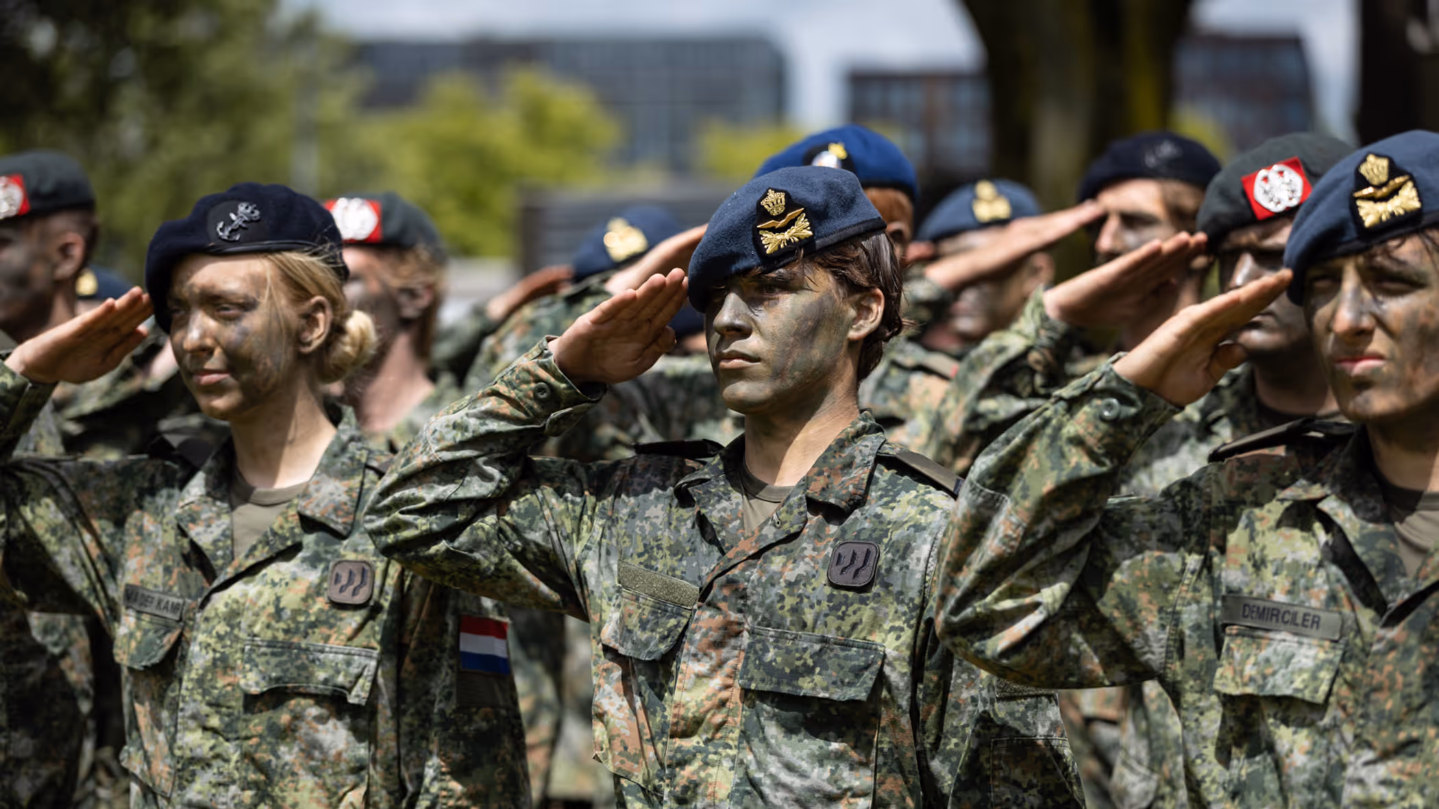 Saluerende militairen met baretten op