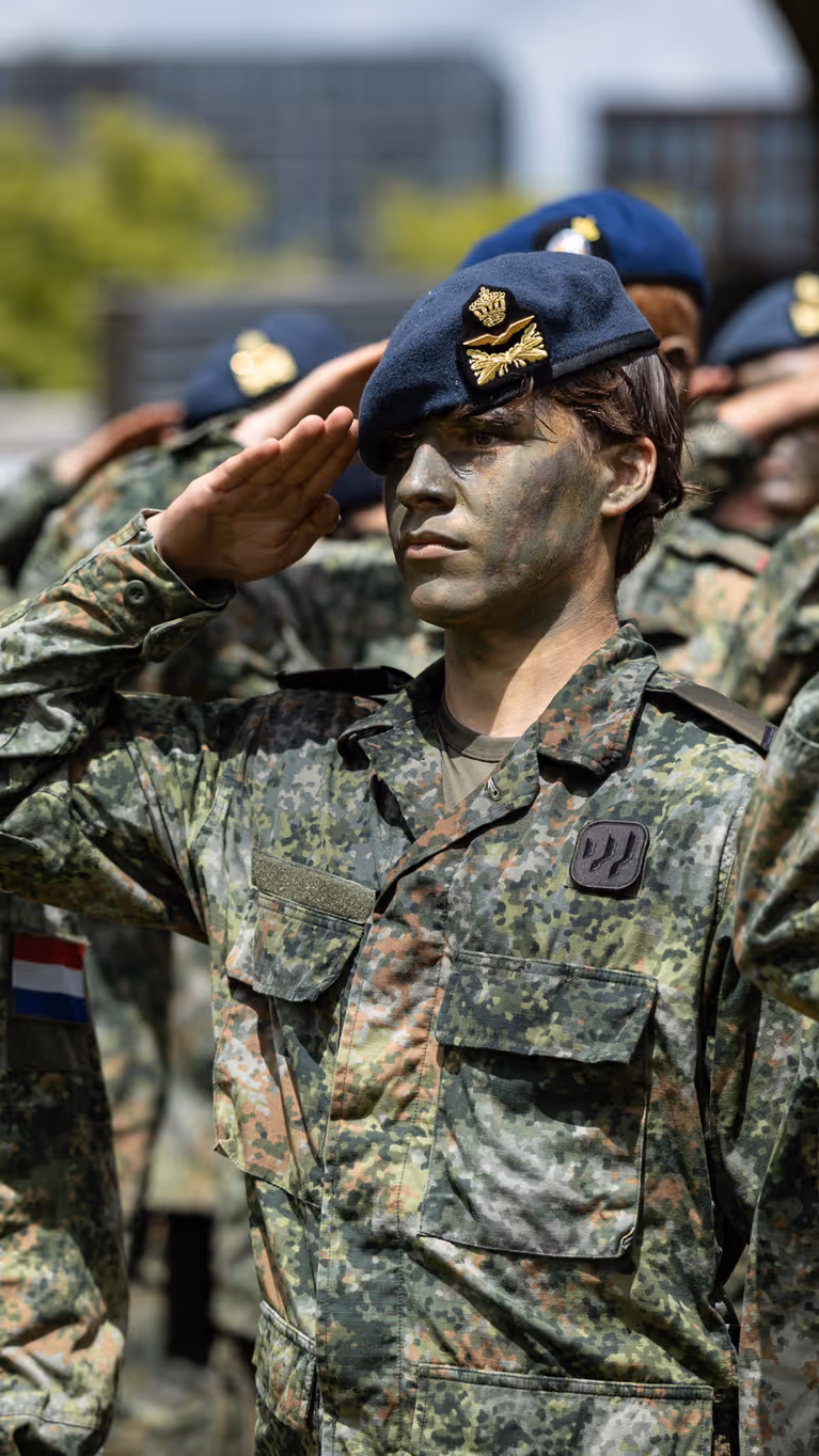 Saluerende militairen met baretten op
