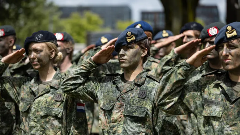 Saluerende militairen met baretten op