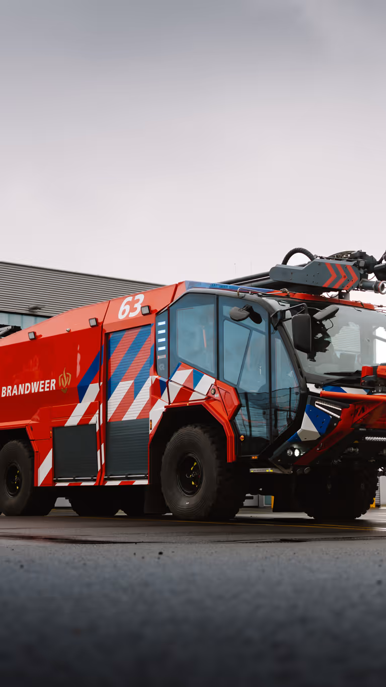 Brandweervoertuig geparkeerd op een luchthaven. 