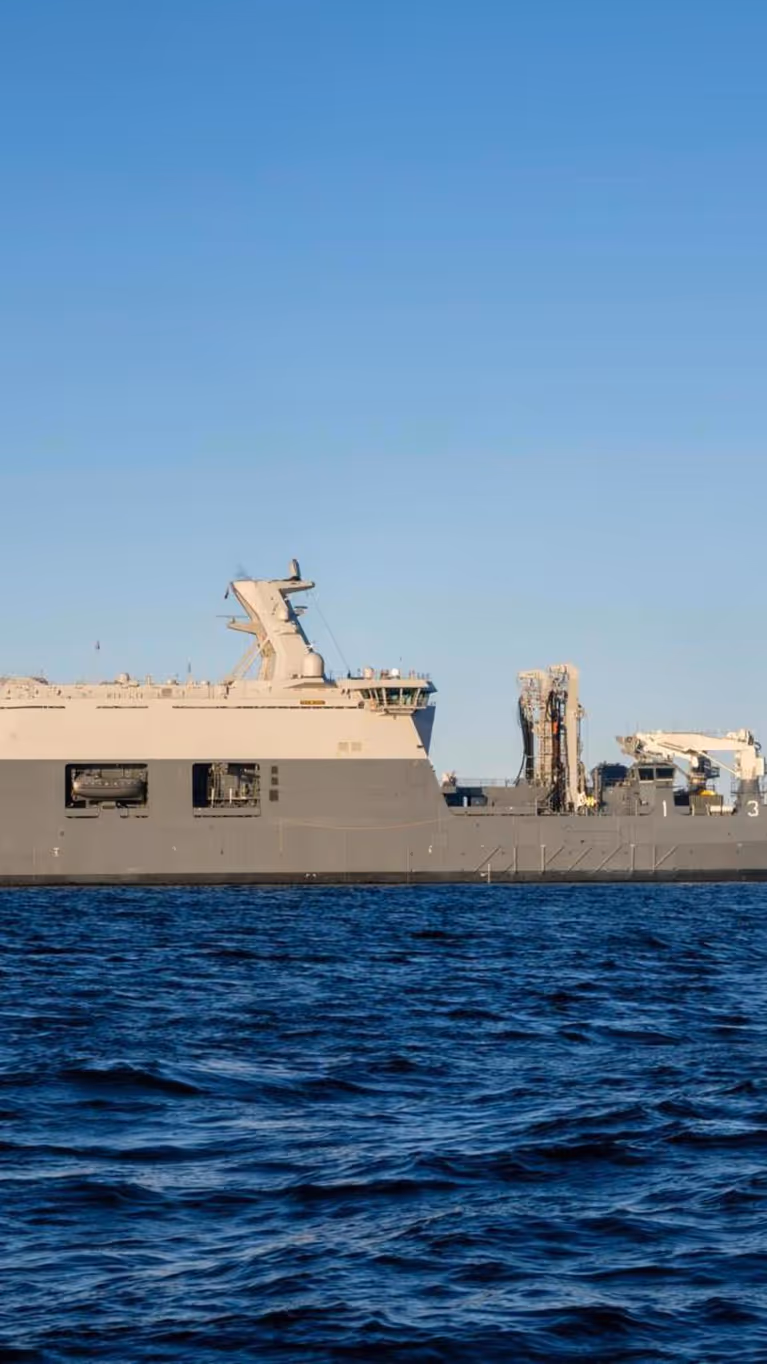 Het grijskleurige marineschip Zr.Ms. Den Helder dobbert op zee. 