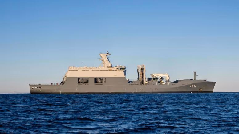 Het grijskleurige marineschip Zr.Ms. Den Helder dobbert op zee. 