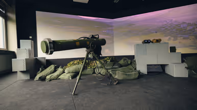 Een viertal afbeeldingen. Naast het cilindervormige, donkergroene antitankwapen Spike Long Range gericht op een beamer, hetzelfde middel alleen nu met daarachter een militair. Samen met een instructeur, die achter een beeldscherm zit, bevinden de twee zich in een kleinere ruimte. Vervolgens diezelfde oefenende militair schuin vanaf onder en gezien vanaf voren. Daarbij is zijn geconcentreerde blik zichtbaar.