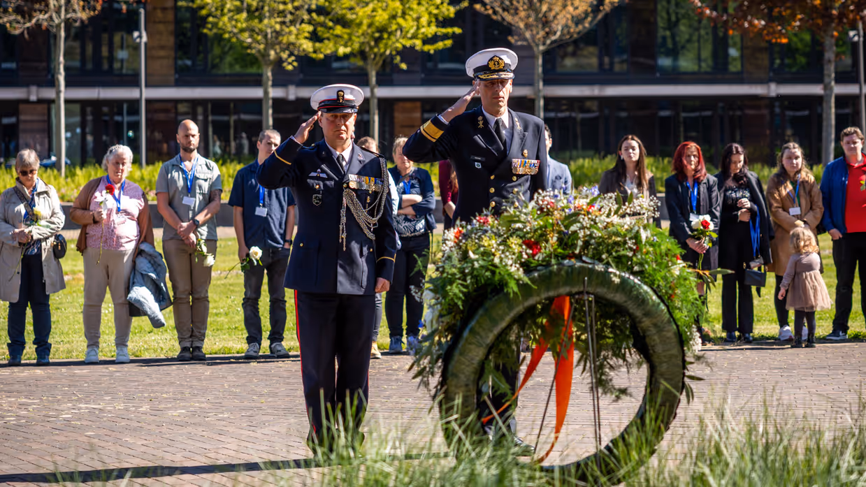 Vice-admiraal Jan Willem Hartman en adjudant Johan Nagel salueren naar de zojuist gelegde krans. Achter hen staan de nabestaanden. 