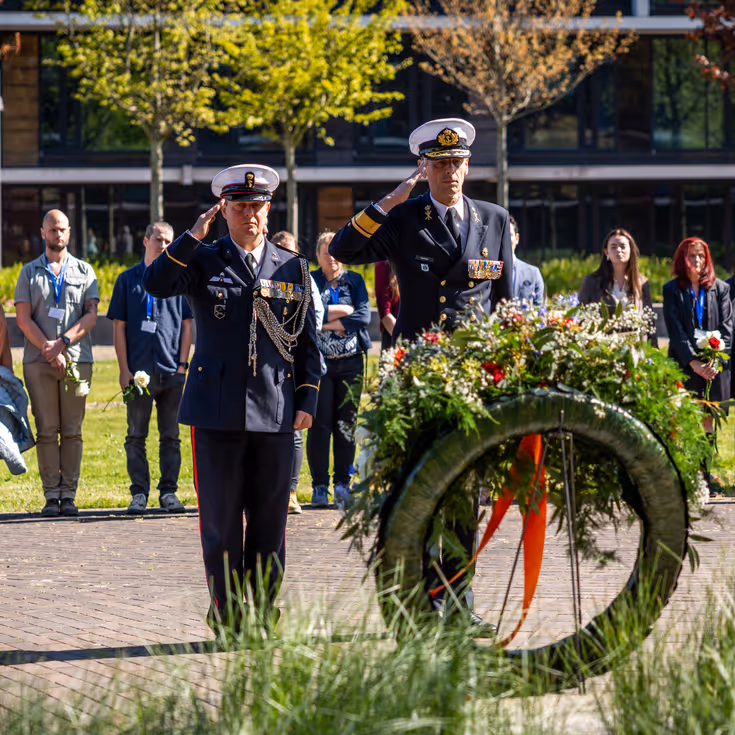 Vice-admiraal Jan Willem Hartman en adjudant Johan Nagel salueren naar de zojuist gelegde krans. Achter hen staan de nabestaanden. 
