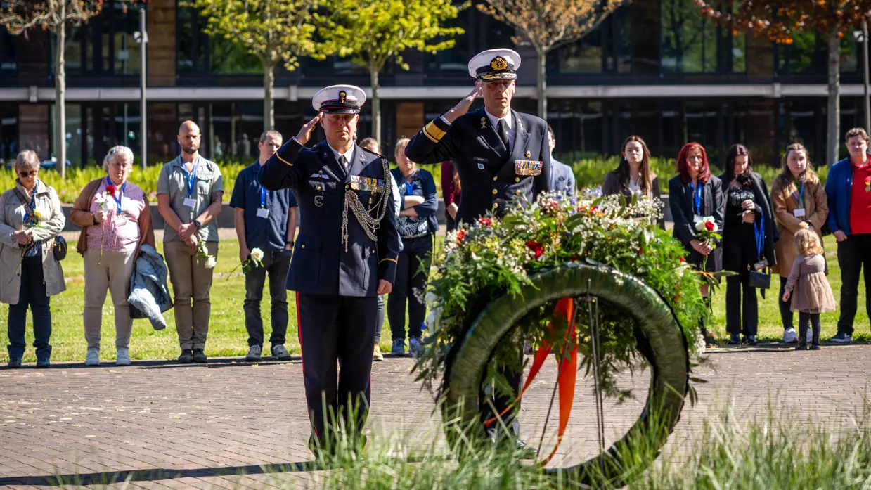 Vice-admiraal Jan Willem Hartman en adjudant Johan Nagel salueren naar de zojuist gelegde krans. Achter hen staan de nabestaanden. 