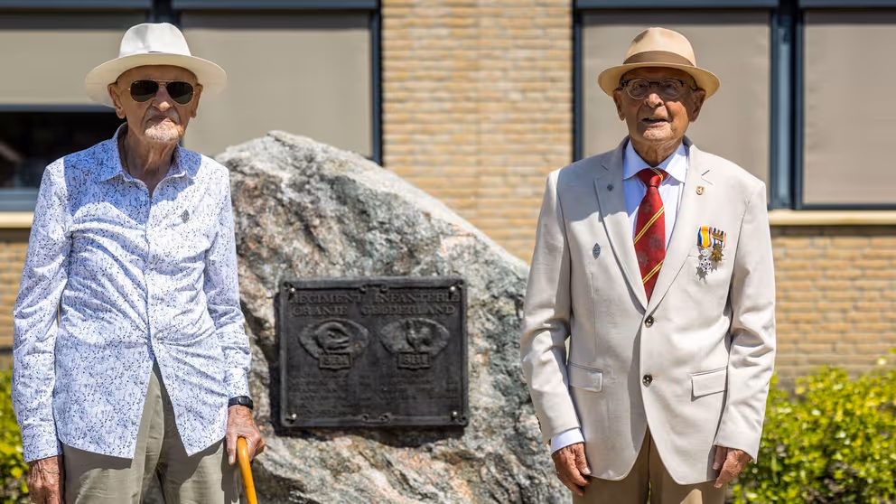 Twee veteranen poseren naast een monument.