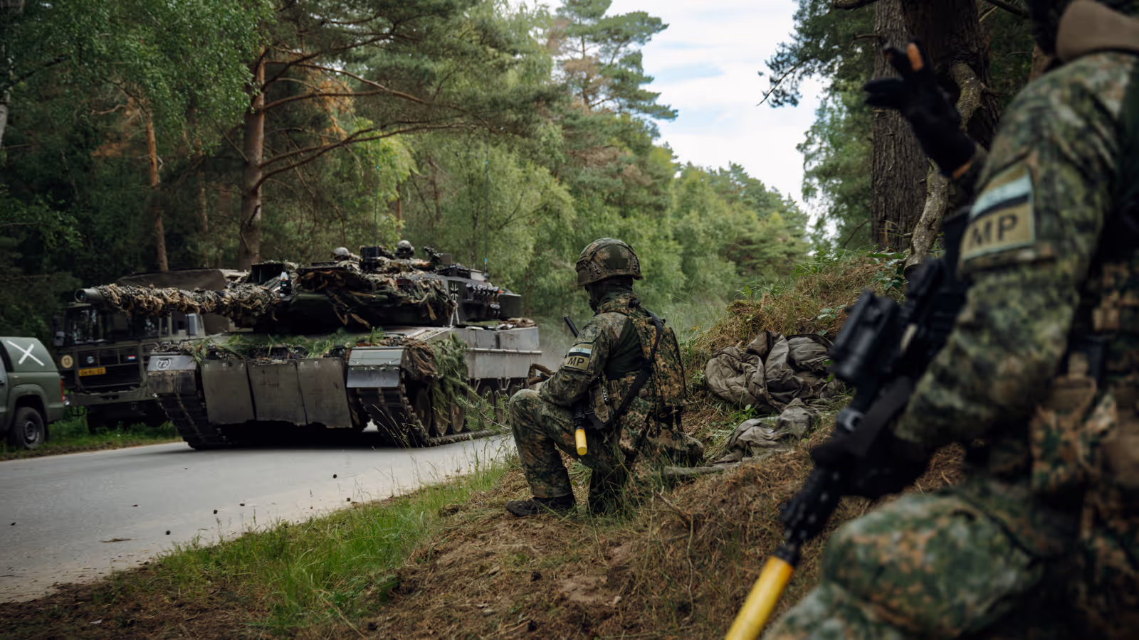 Marechaussees van 103 Marechaussee Eskadron met op de achtergrond een voertuig van de Landmacht.