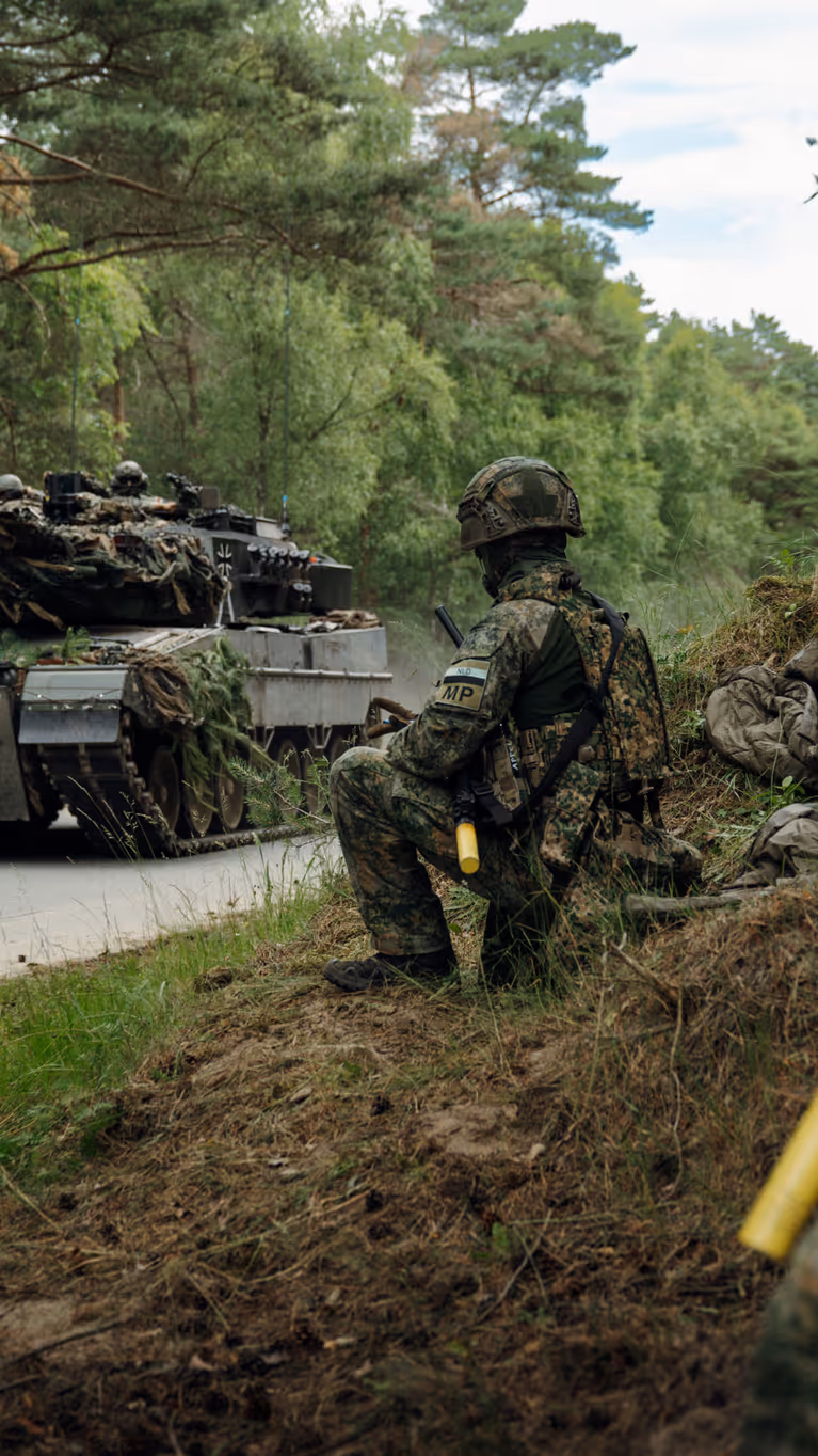 Marechaussees van 103 Marechaussee Eskadron met op de achtergrond een voertuig van de Landmacht.