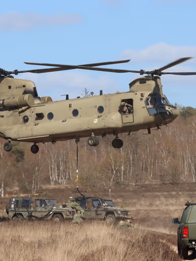 Links: militairen te velde, met op de achtergrond een militaire helikopter. Rechts: Een helikopter stijgt op, eronder is een auto bevestigd aan een kabel.