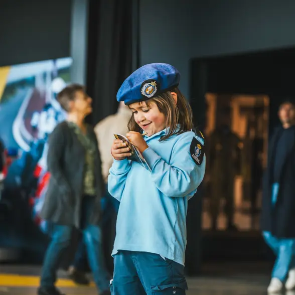Klein meisje in Marechaussee-uniform met een boekje in haar hand.