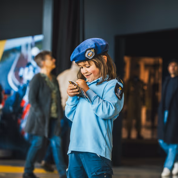 Klein meisje in Marechaussee-uniform met een boekje in haar hand.