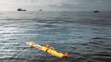 Marinecollega’s met een bouwvakkershelm op zijn bezig met een zeedrone die in de takels hangt. Op de andere foto ligt de gele zeedrone in het water, op de achtergrond zijn marineschepen te zien. 