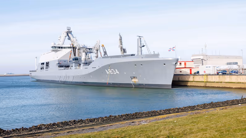 Het grijze marineschip ligt aan de kade.