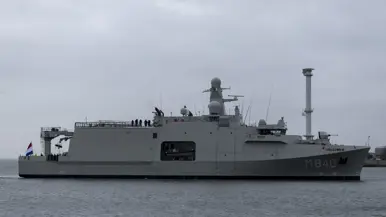 Het varende, grijze marineschip vanaf de zijkant. Daarnaast een afbeelding met daarop een deel van de bemanning bij de reling van het schip, daarachter een wapperende Nederlandse vlag. Vervolgens saluerende militairen vanaf de brug van de Vlissingen en een groepje marineofficieren dat het schip vanaf de kade aanschouwt en vastlegt met de mobiele telefoon.