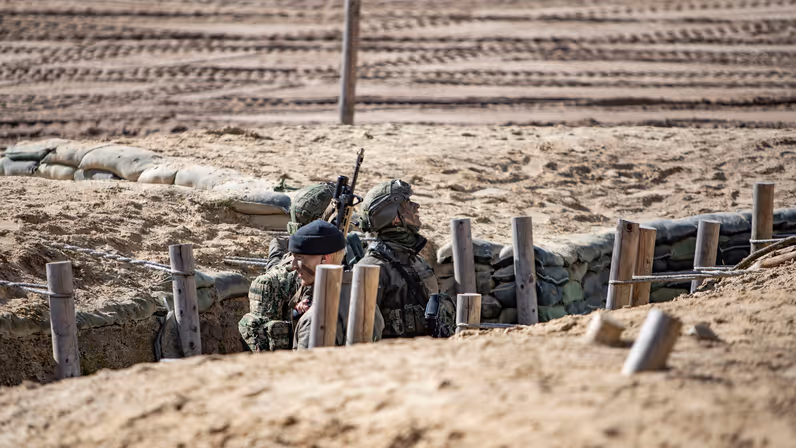 Militairen nemen positie in een loopgraaf tijdens een oefening in het veld.