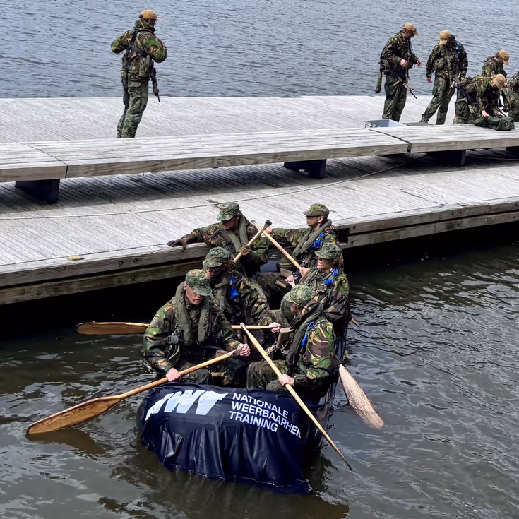 De deelnemers aan de NWT roeien in rubberboten door Amsterdam.