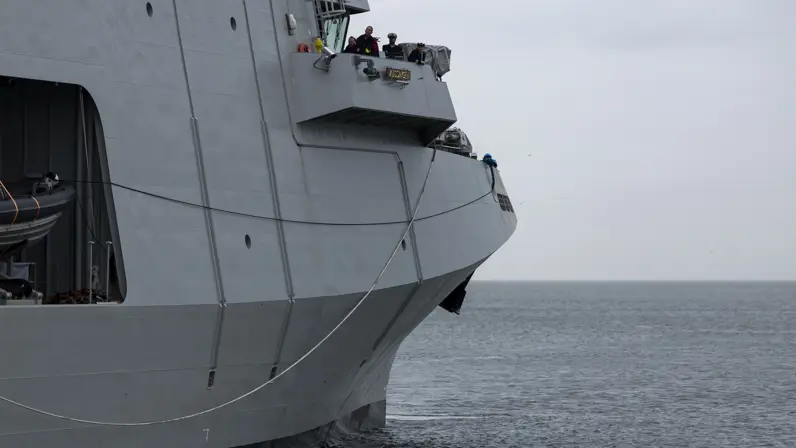 Het voorste gedeelte van het varende marineschip. Op de afbeelding is de brug te zien, waarop enkele militairen van de marine staan. 