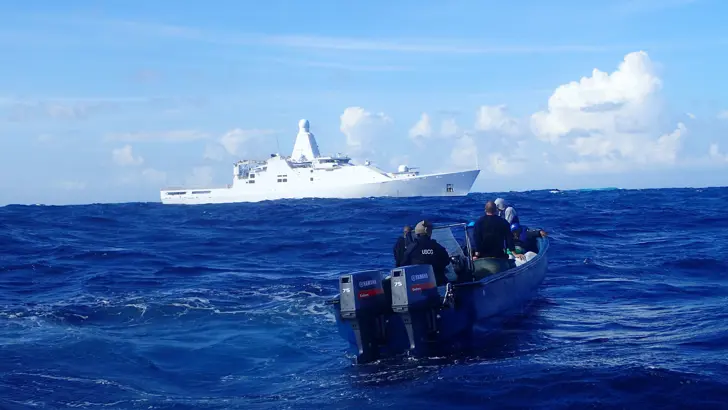 Patrouilleschip Zr.Ms. Friesland met op de voorgrond een drugssmokkelboot.