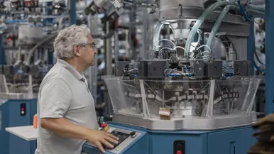 Een man bedient een knoppenpaneel van een grote machine. 