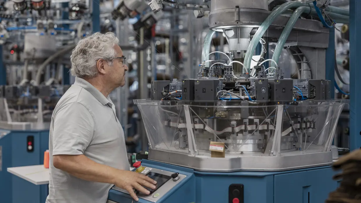 Een man bedient een knoppenpaneel van een grote machine. 