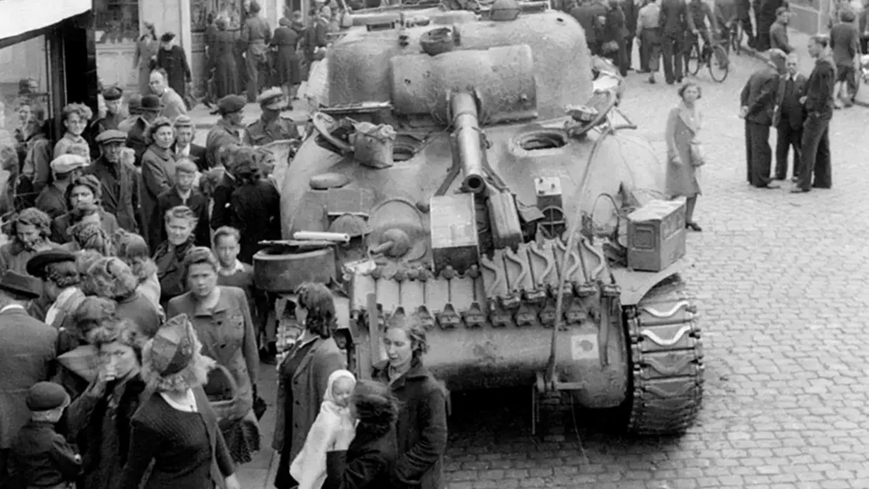Een tank rijdt door een drukke straat, omringd door nieuwsgierige burgers in een zwart-wit stadstaferelen.    