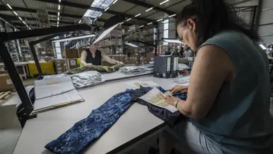 Twee vrouwen werken aan een tafel aan militaire kledingstukken.