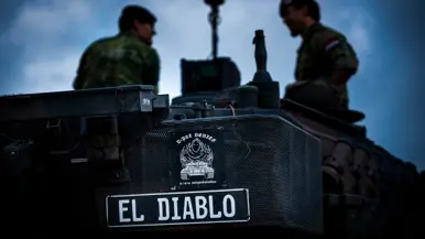 Een naamplaat met El Diablo op de achterkant van een tank, met het silhouet van twee militairen op de achtergrond.