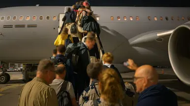 Mensen in burgerkleding vormen een rij voor en op de vliegtuigtrap van een A330 MRTT.