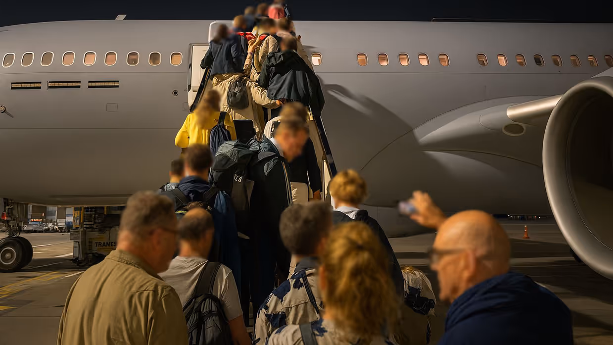 Mensen in burgerkleding vormen een rij voor en op de vliegtuigtrap van een A330 MRTT.