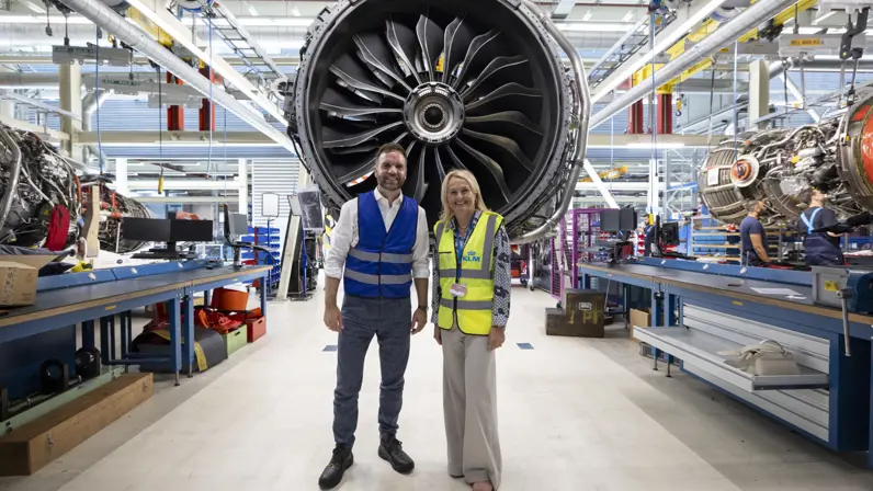 Staatssecretaris van Defensie Derk Boswijk samen met KLM CEO Marjan Rintel poserend voor een vliegtuigmotor op een vliegtuigwerkplaats.