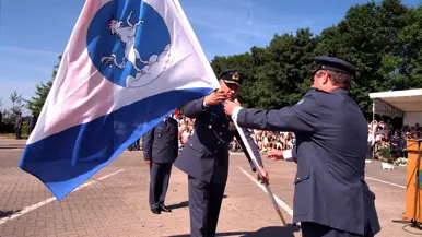 Twee militairen dragen een vlag aan elkaar over.