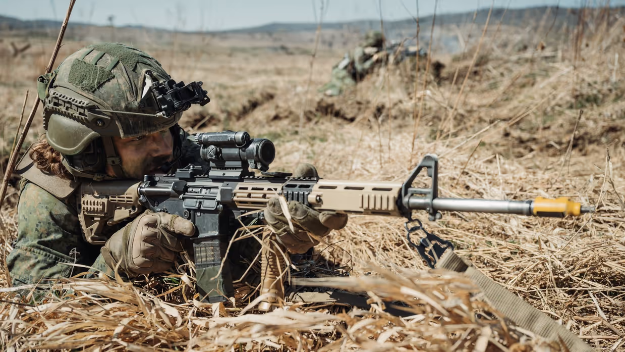 Militair ligt op zijn buik en richt een wapen.