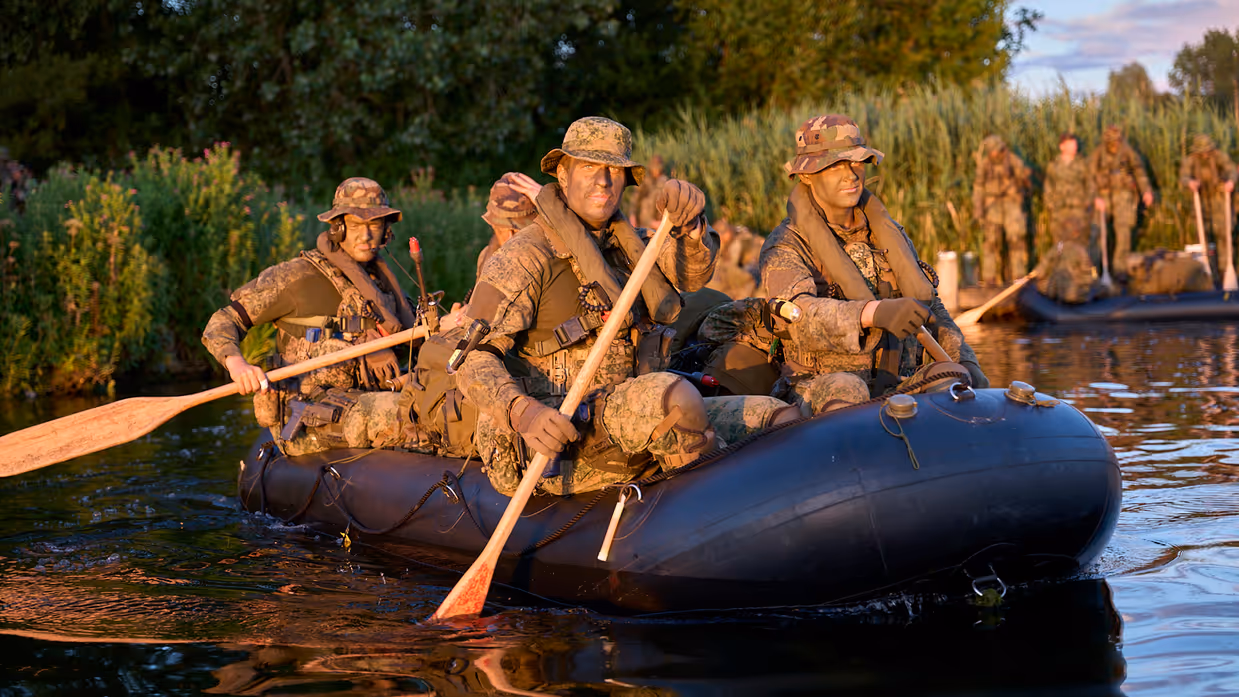 Mariniers roeien met rubberboten over een watertje.