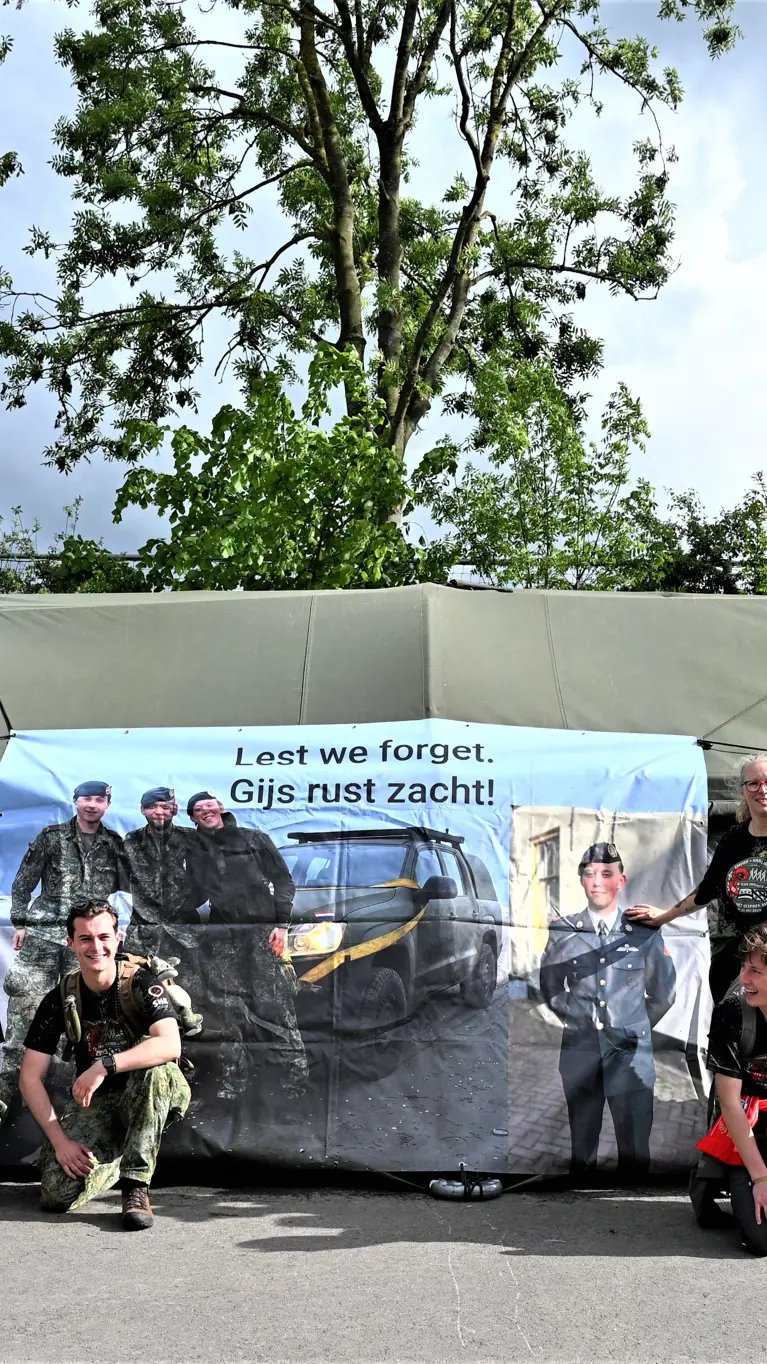 De lopers voor een groene tent waar een banner aan hangt.  