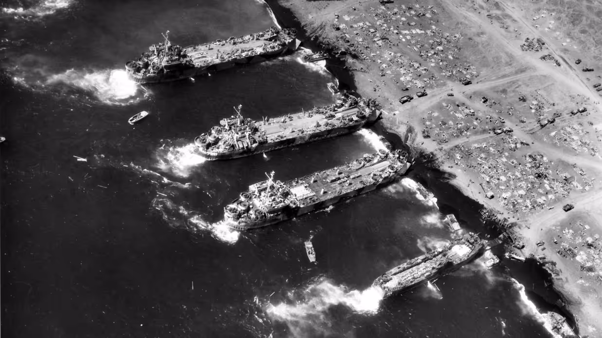 Alttekst: Vanuit de lucht zijn vier schepen aan een strand te zien en veel rommel op het strand. 