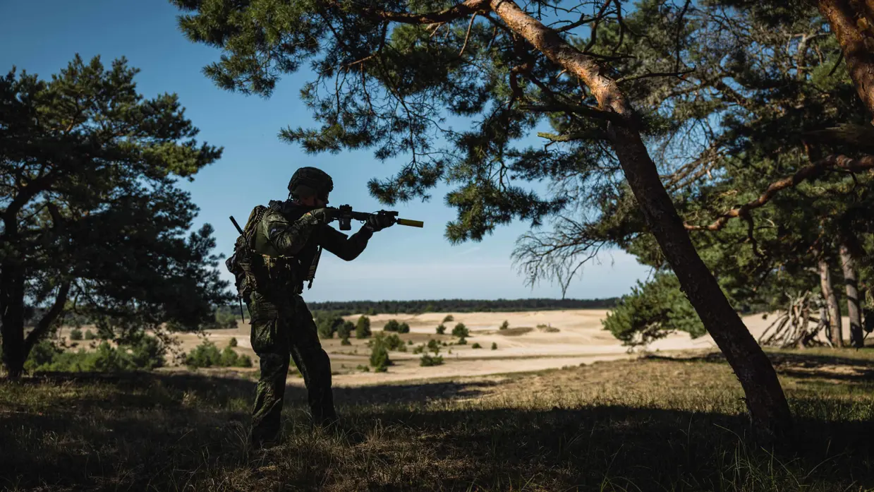 Militair van de Marechaussee in groen tenue tijdens contactdrill op de heide.