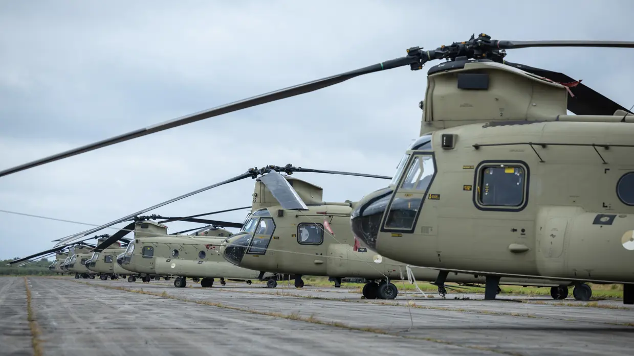 Een rij Chinooks opgesteld. Daarnaast een rij Apaches opgesteld. 