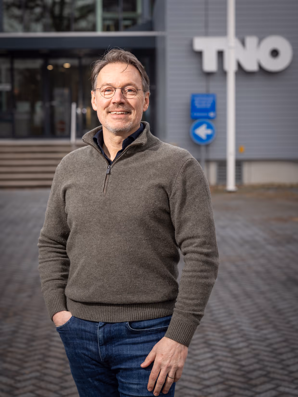 Portretfoto van Rajko Brokken. Vaag op de achtergrond is de afkorting TNO te zien.