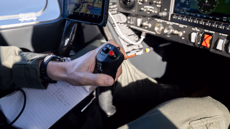 Vlieger bedient de stuurknuppel in de cockpit van het KMar-patrouillevliegtuig tijdens een vlucht. 